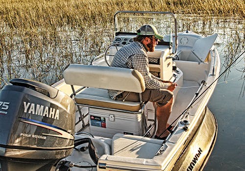 A solo fisherman aboard his boat in shallow waters